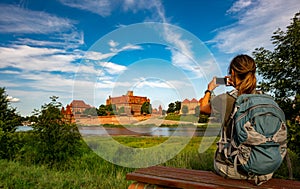 Tourist Backpacker woman takes picture of Malbork Castle