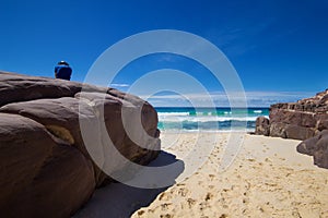 Tourist with backpacks on a large stone and enjoying Sea View. Ben Boyd national park, Australia photo