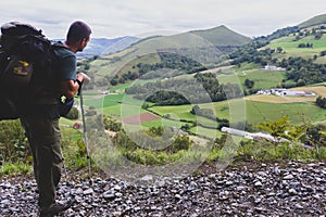 Tourist with big backpack and sticks on the top of Pyrenees mountains, toned. Pilgrim on Camino de Santiago, France.