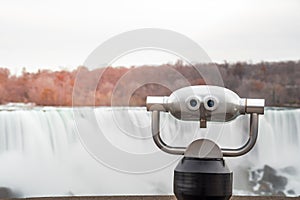 Tourist Binocular with a Waterfall in Background at Sunset photo