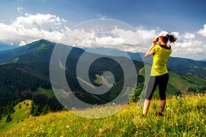 Turista s ďalekohľadom pri pohľade z kopca na krásnu prírodu