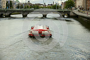 tourist boat crossing the liffey river through the center of Dublin heading