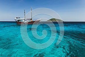 Tourist boat near island shore with turquoise clear transparent water