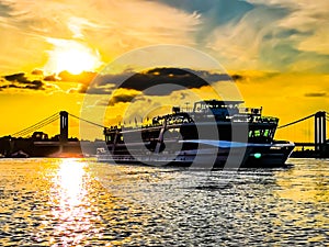 Tourist boat at the riverside of the river Rhein in Cologne with sunlight  on the blue water and clouds