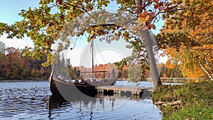 The Tourist Boat in the Style of a Viking Ship on the River Perse. Autumn Old Koknese Castle Ruins.