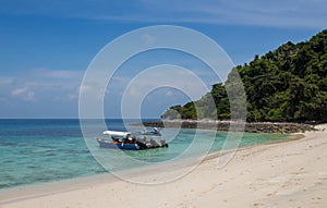 Tourist boats moored on a beach on the tropical island of Pulau Tulai, Malaysia