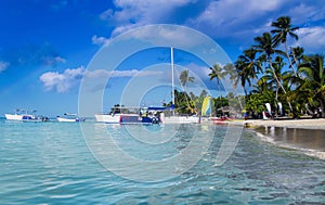 Tourist boats off the coast of the Caribbean Sea. The beach of the island Saona in cloudy weather. Rainbow over the island