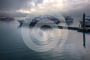 Tourist boats parking on peaceful water and moored to the floating docks of Shuishe Pier at Sun-Moon Lake