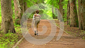 Tourist boy enjoying hiking with backpack in national park. Happy child walking in the forest in summer. Active