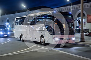 Tourist bus moves at night on a city street