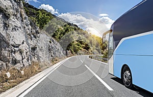 Tourist bus rushes along the country high-speed highway against the background of a mountain landscape.