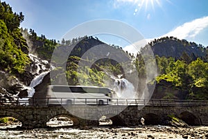 Tourist bus traveling on the road Latefossen Waterfall Odda Norway. Latefoss is a powerful, twin waterfall