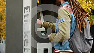 A tourist buys a ticket for public transport bus or subway. Hipster with dreadlocks buys a ticket in the electronic