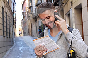 Tourist calling by phone while looking at tourism guide or dictionary