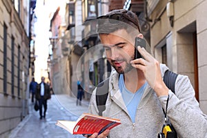 Tourist calling by phone while looking at tourism guide or dictionary