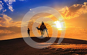 Tourist on camel safari in silhouette at the Thar desert Jaisalmer Rajasthan, India