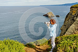 Tourist with camera on Asturias coast. Cabo Busto cliffs, Spain