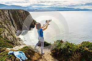 Tourist with camera on Asturias coast. Cabo Busto cliffs, Spain photo