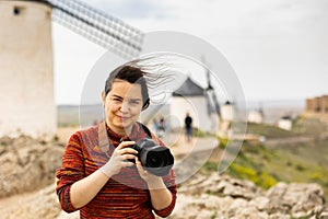 Tourist with camera in front of the windmills in Spanish city of Consuegra