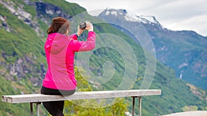 Tourist with camera looking at scenic view in mountains Norway