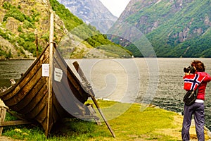 Tourist with camera near old viking boat, Norway