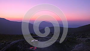 Tourist camp in the mountains. A teapot is warming on a fire in the background of a beautiful mountain landscape after sunset.