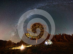 Tourist camping and tent under night sky full of stars