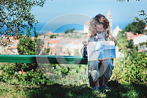 Tourist child girl with map traveling on summer vacations in Piran