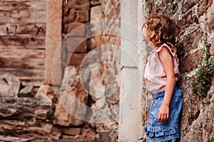 Tourist child girl at stone wall on the walk in Piran, Slovenia