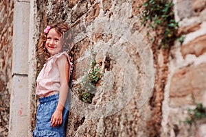 Tourist child girl at stone wall on the walk in Piran, Slovenia