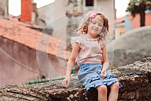 Tourist child girl at stone wall on the walk in Piran, Slovenia