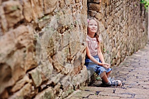 Tourist child girl at stone wall on the walk in Piran, Slovenia