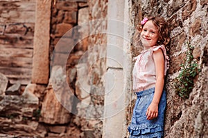 Tourist child girl at stone wall on the walk in Piran, Slovenia