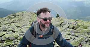 Tourist climber with a backpack, having a hike in the mountains, looks around.