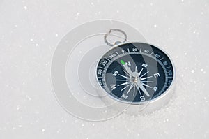 Tourist compass on a background of white snow on a sunny day