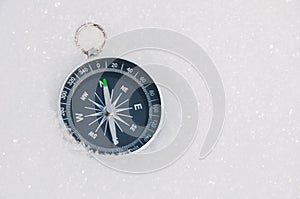 Tourist compass on a background of white snow on a sunny day