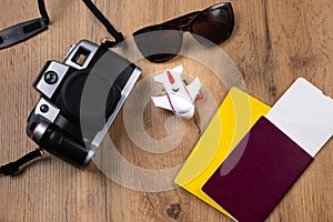Tourist concept, background of a wooden table with necessary documents prepared for the trip, sunglasses and a photo camera. Safe