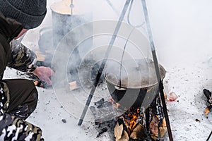 Tourist cooking food on bonfire, cooking on snow in winter. Preparation food for breakfast, lunch and dinner