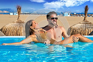 Tourist couple bath in infinity pool on a beach