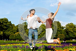 Tourist couple in city park jumping in sun