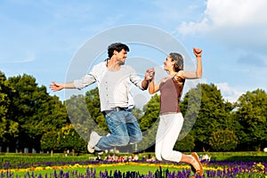 Tourist couple in city park jumping in sun