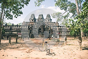 Tourist couple cycling around Angkor temple, Cambodia. Ta Keo building ruins in the jungle. Eco friendly tourism traveling