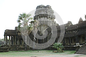 Tourist couple cycling around Angkor temple, Cambodia. Ta Keo building ruins in the jungle.