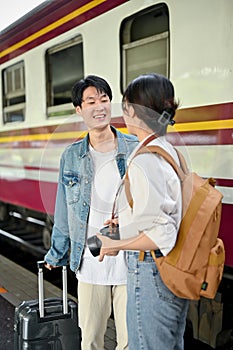 A tourist couple enjoys talking before boarding the train at the railway station together