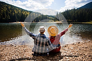 Tourist couple in hat raising arms and overlooking turquoise lake