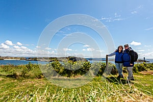 Tourist couple on a hill on Inishbofin or White Cow Island with the Atlantic Ocean in the background photo