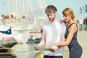 Tourist couple in marina looking up directions on map