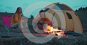tourist couple sitting next to the tent bonfire on the mountains