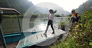 Tourist couple walking towards the boat on the calm lake on a sunny day.