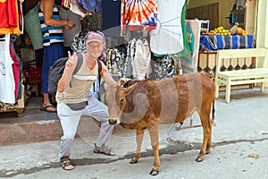 Tourist with a cow in front of a clothing shop in Laxman Jhula India